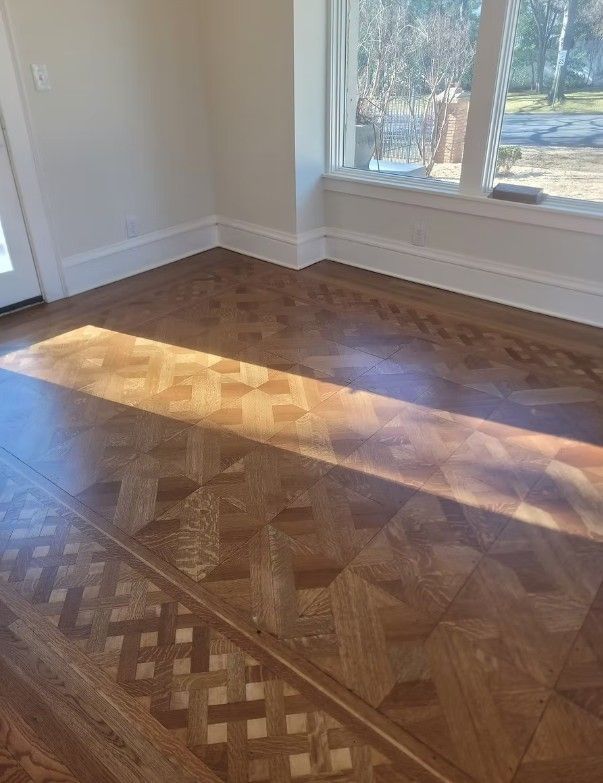 Empty room with parquet wood floor and sunlight streaming through a window