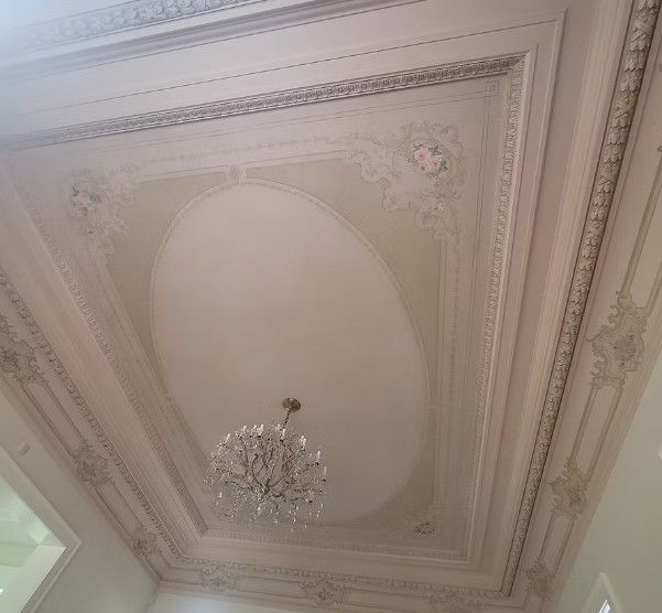 Ornate white ceiling with decorative molding and a central crystal chandelier