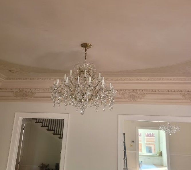 Elegant crystal chandelier hanging from a cream-colored ceiling in a softly lit room.