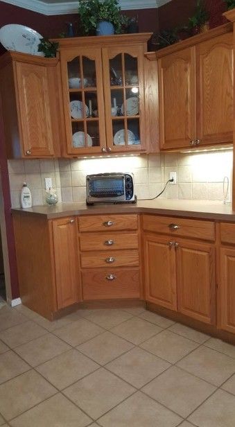 Kitchen corner with honey-oak cabinets, beige tile floor, and a toaster on the countertop.