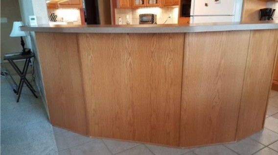 Curved wooden reception counter in a tiled lobby area with chairs and warm lighting in the background
