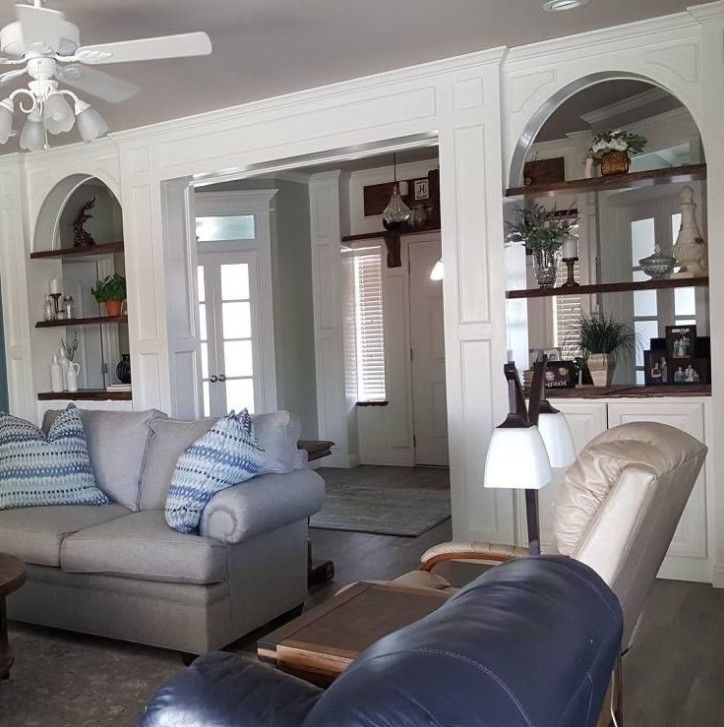 Bright living room with a white fireplace, built-in shelves, and beige and blue sofas and chairs.