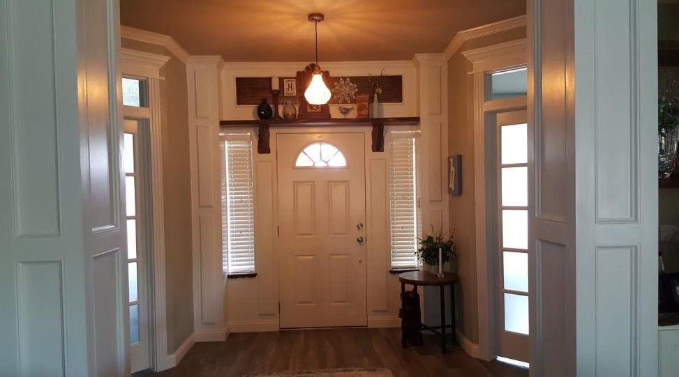 Front entryway with white front door, sidelights, warm hanging light, and wood floors
