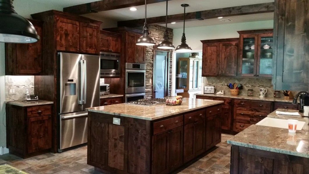 Modern kitchen with dark wood cabinets, stainless steel appliances, and granite island countertops