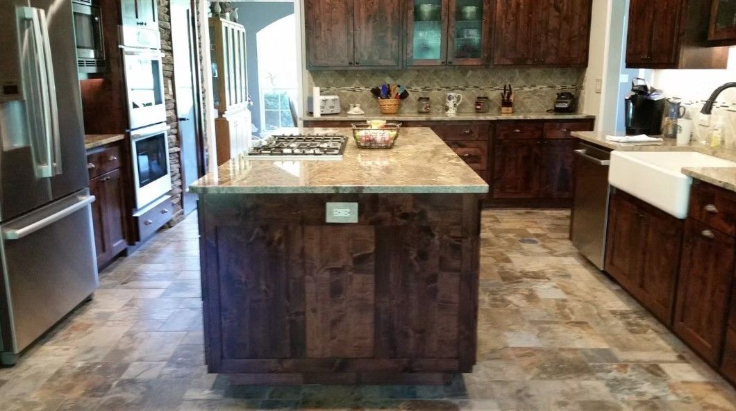 Modern kitchen with dark wood cabinets, granite island, and tile floor