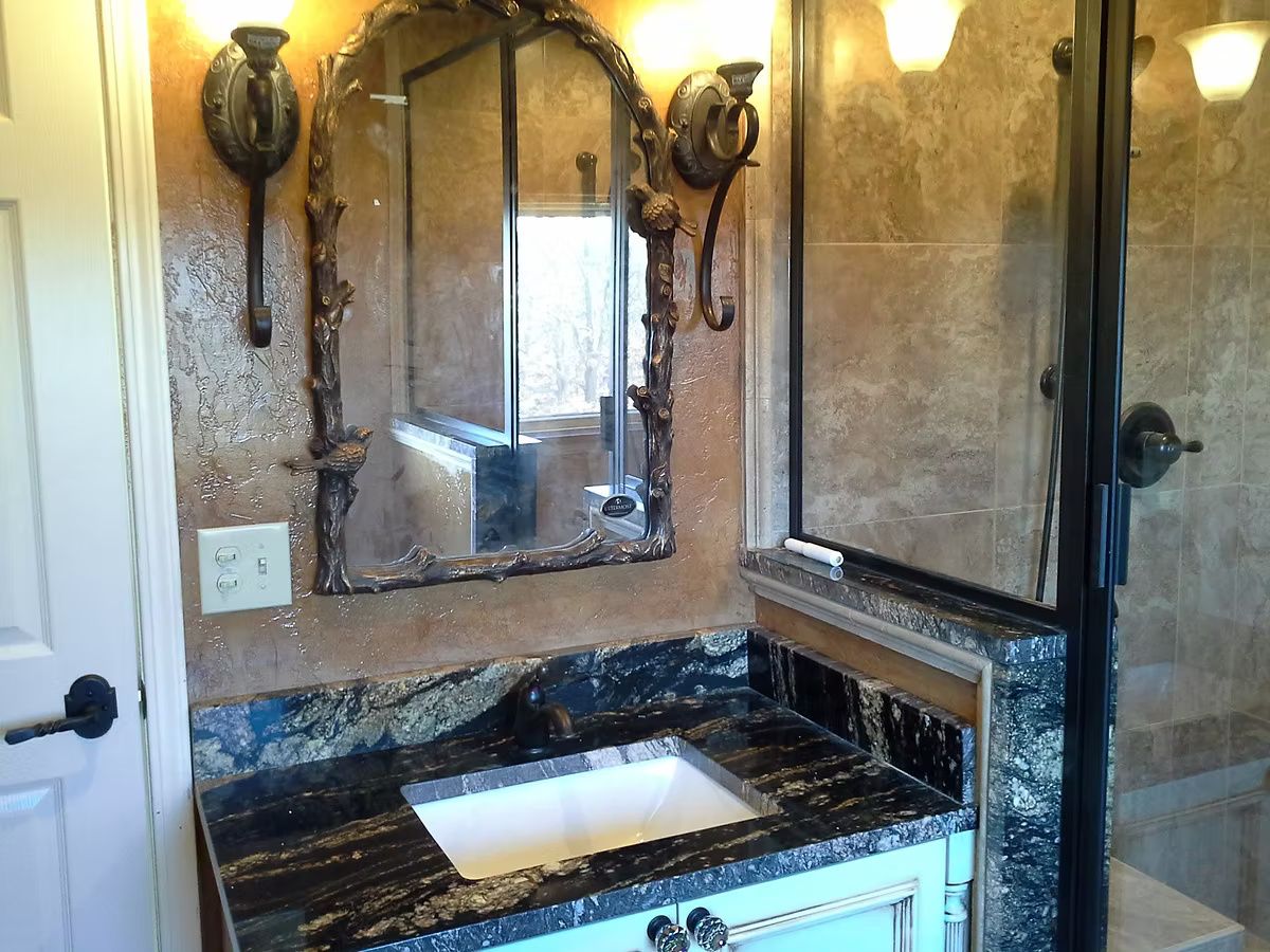 Bathroom vanity with mirror, sconces, and dark marble countertop with sink