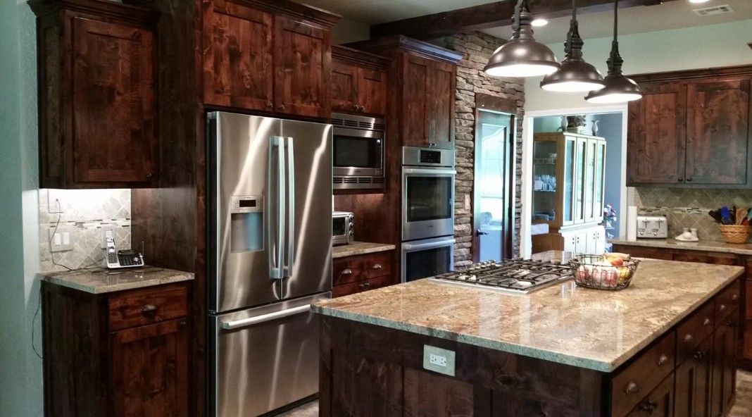 Modern kitchen with dark wood cabinets, stainless steel appliances, and a large granite island