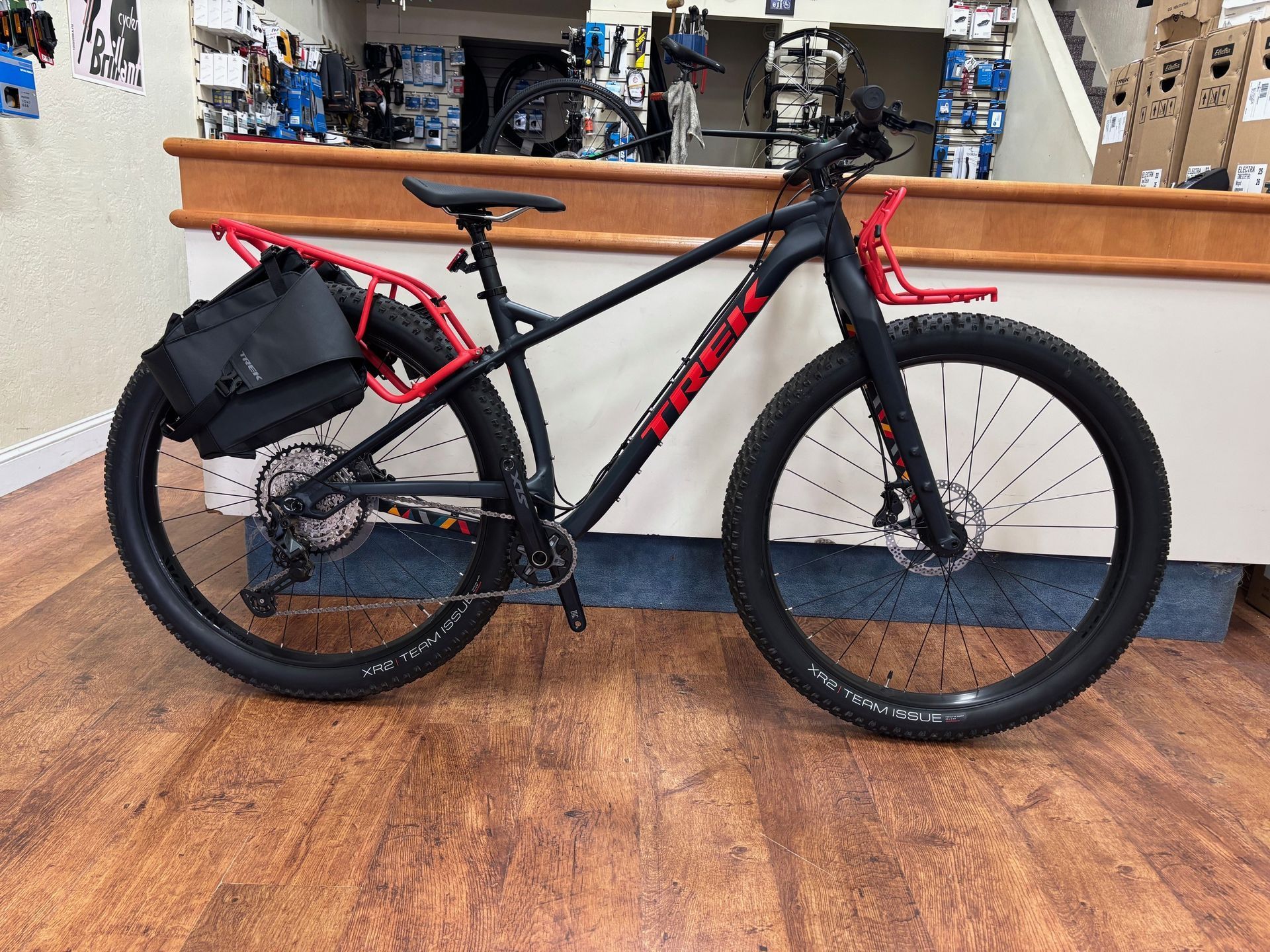 A black and red bicycle is parked on a wooden floor in a store.