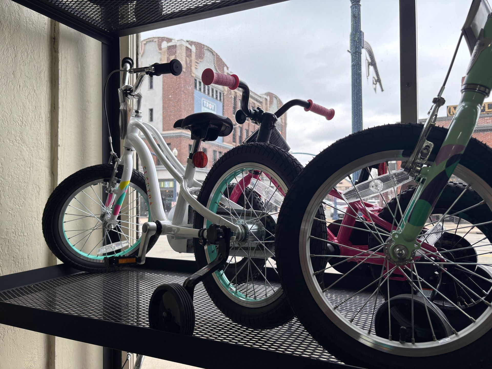 A row of bicycles are sitting on a shelf in front of a window.