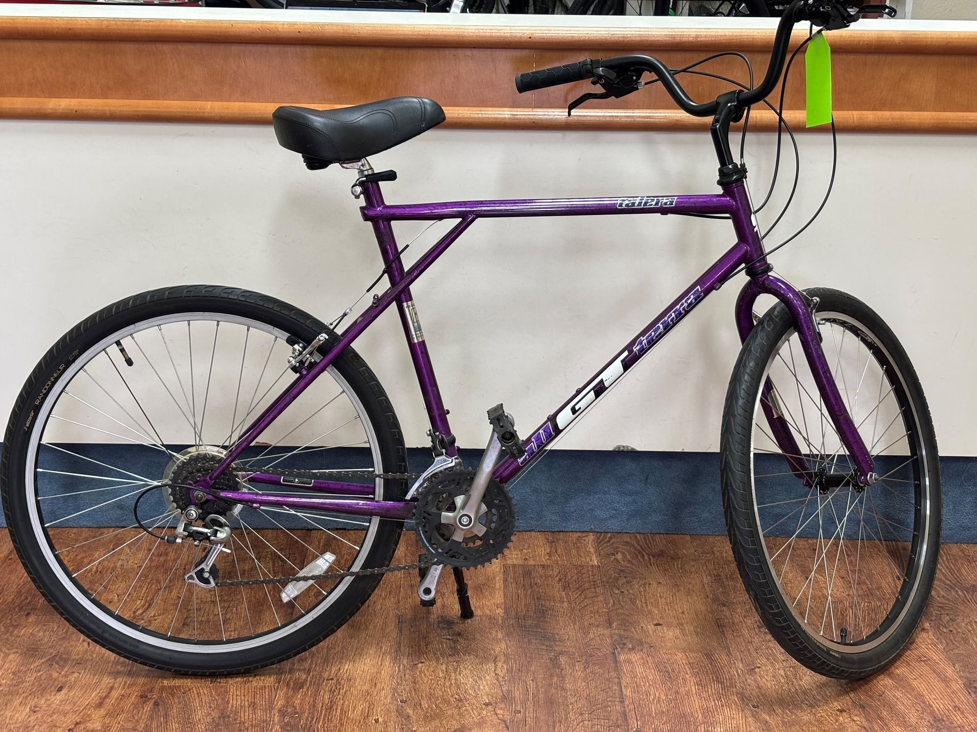 A purple bicycle is sitting on a wooden floor.