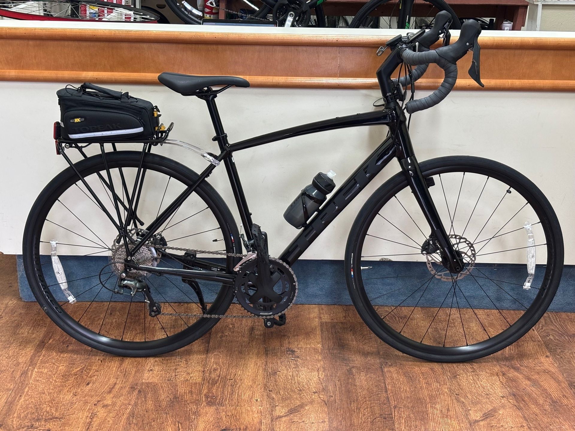 A black bicycle is parked on a wooden floor in a store.