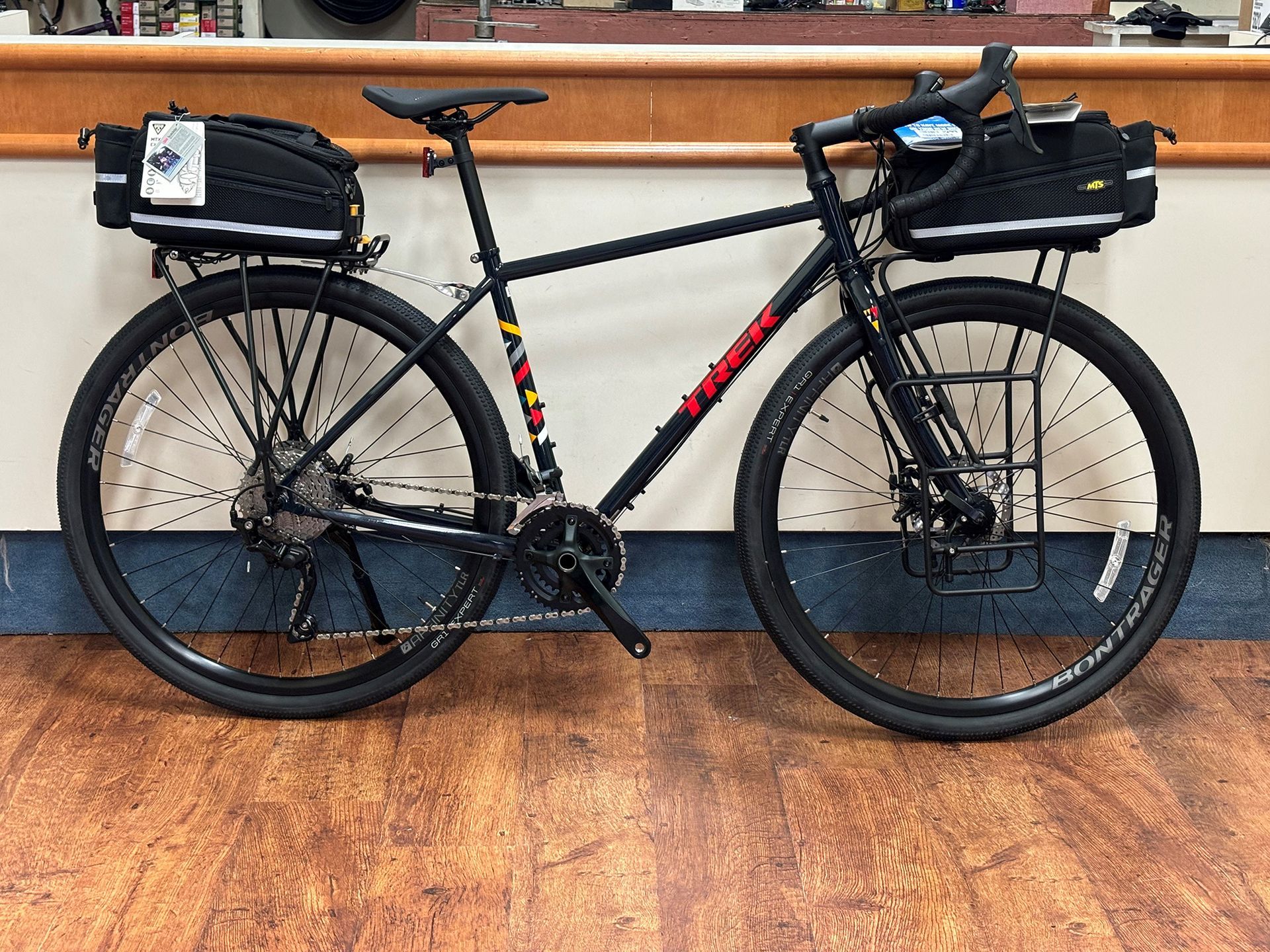 A bicycle is parked on a wooden floor in front of a counter.