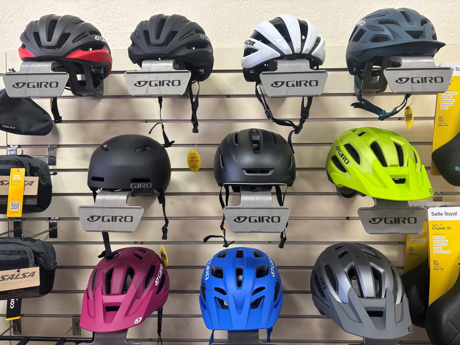 A variety of bicycle helmets are displayed on a wall in a store.