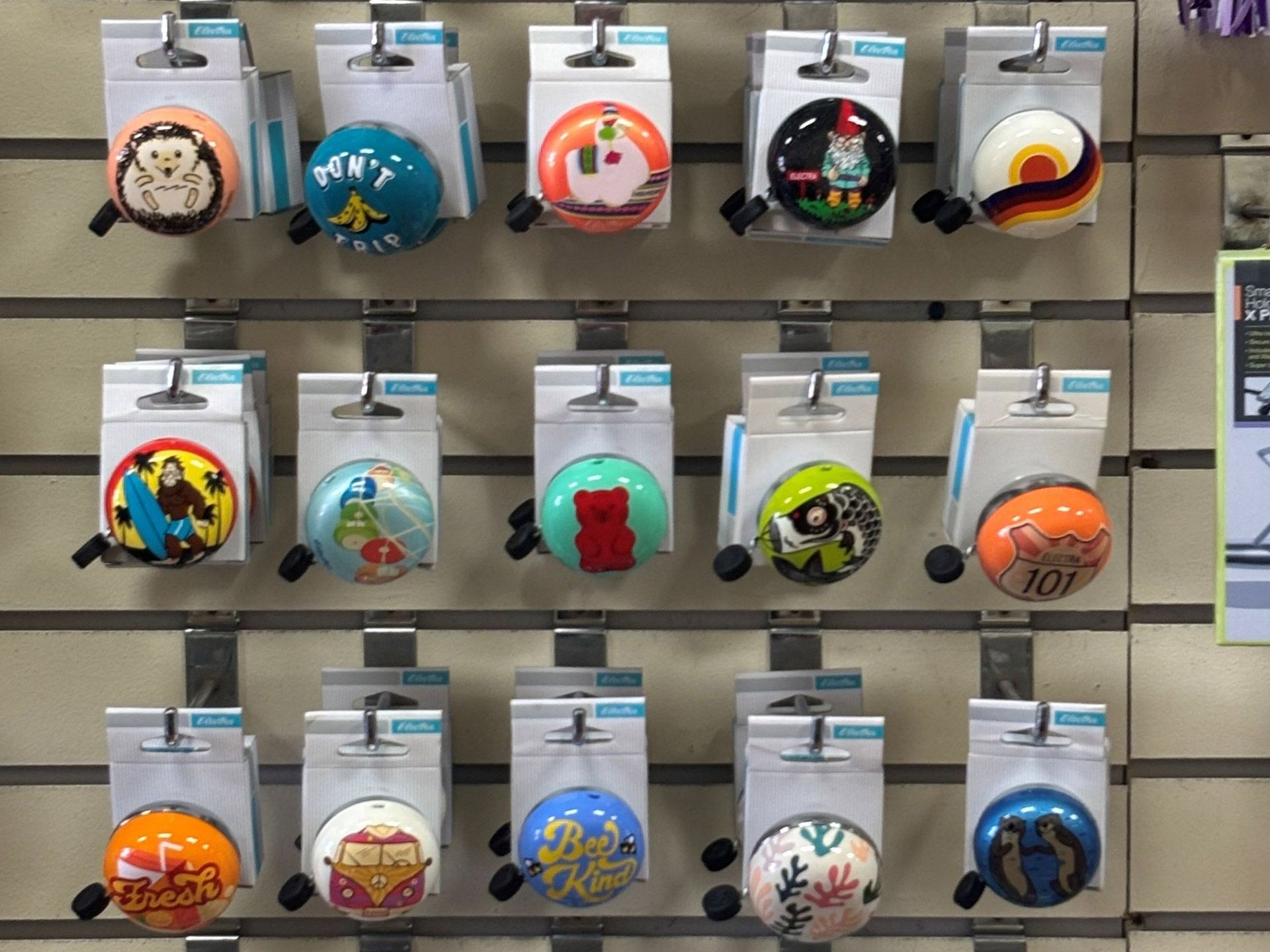 Bike bells with various decorative designs displayed on a store rack.