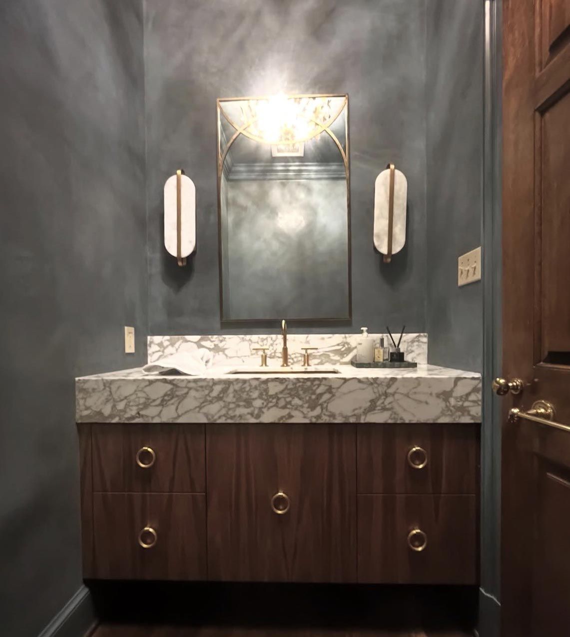 A luxurious kitchen with dark wood cabinets, black countertops, and an island with bar stools.