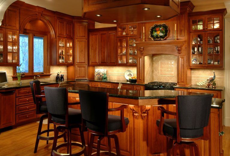 A luxurious kitchen with dark wood cabinets, black countertops, and an island with bar stools.