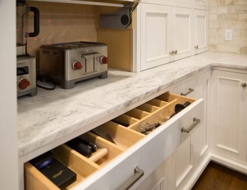 White kitchen with a pull-out drawer containing organized utensils. A toaster and blender sit on the countertop.