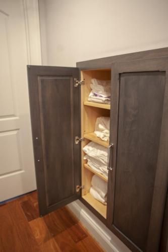 Dark gray cabinet with an open door revealing shelves stocked with white towels in a bathroom.