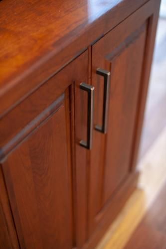 Wooden cabinet doors with dark metal handles. The doors are closed, with a glossy finish.