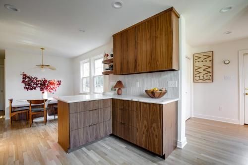 Modern kitchen with wood cabinets, white countertops, and a dining area with a floral wall art.
