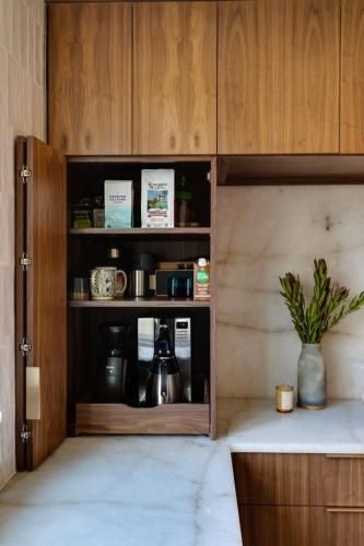 A kitchen cabinet with coffee supplies. It features a built-in coffee maker, coffee, and a marble countertop.