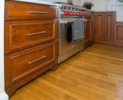 Kitchen with wooden cabinets, stainless steel stove, and light hardwood floors.