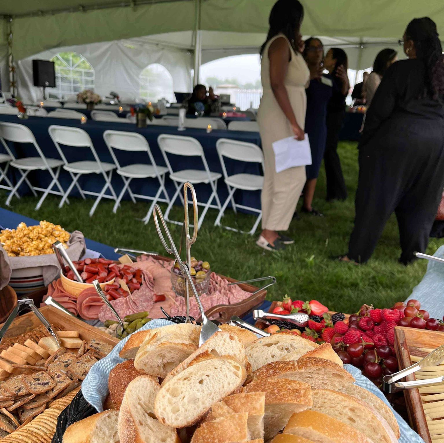 Food spread at outdoor event; people mingling nearby.