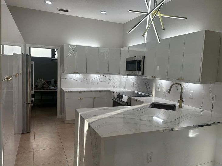 A kitchen with white cabinets and marble counter tops.