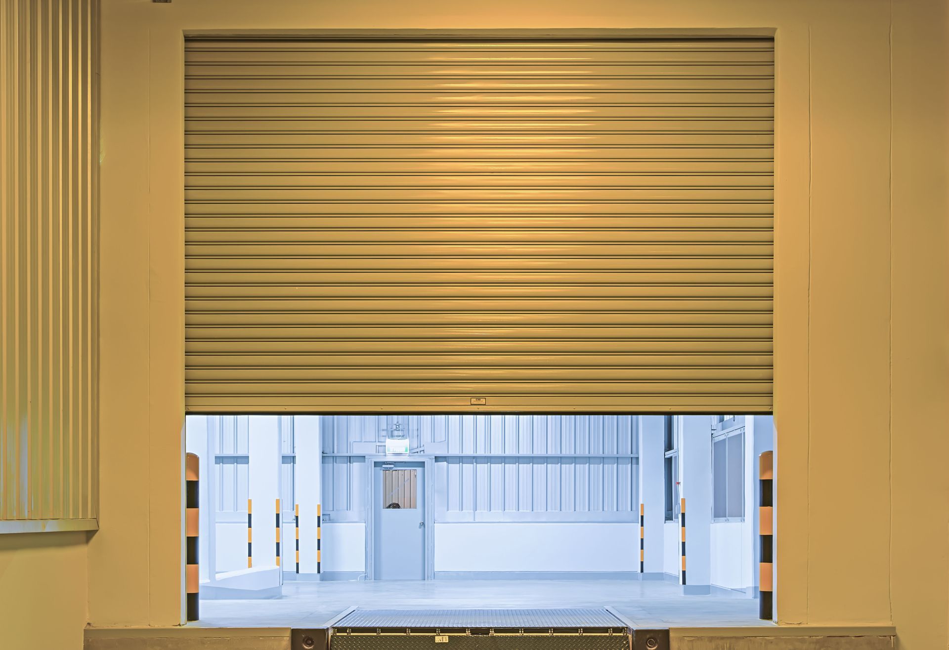 Wooden double doors on gray house, flanked by windows and bushes.