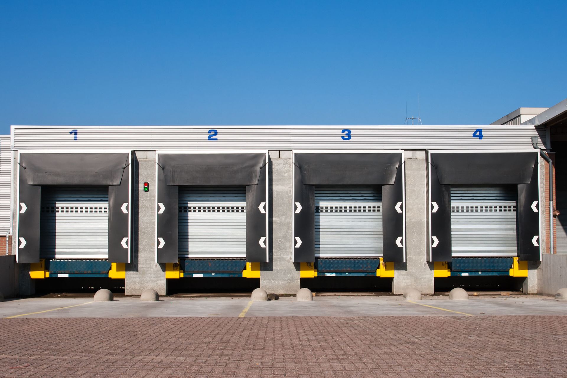 Blue house with white trim, brown door, stone accents, and paved walkway.