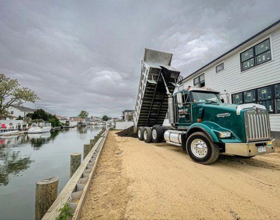 Dump truck unloading dirt near a canal