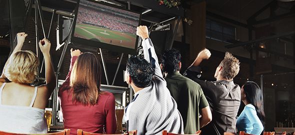 A group of people are watching a soccer game in a bar.