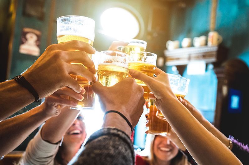 A group of people are toasting with beer glasses in a bar.