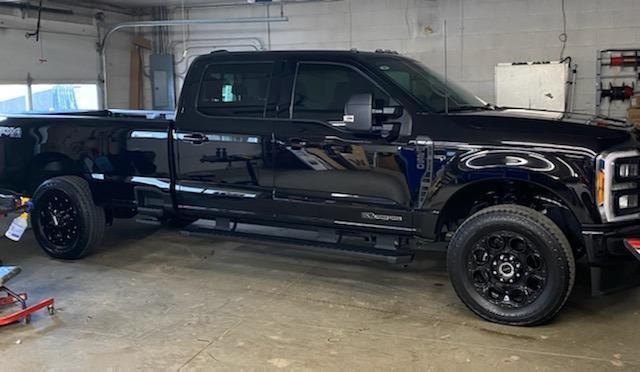 Black Ford F-series truck parked inside a garage. The truck has black wheels and tinted windows.