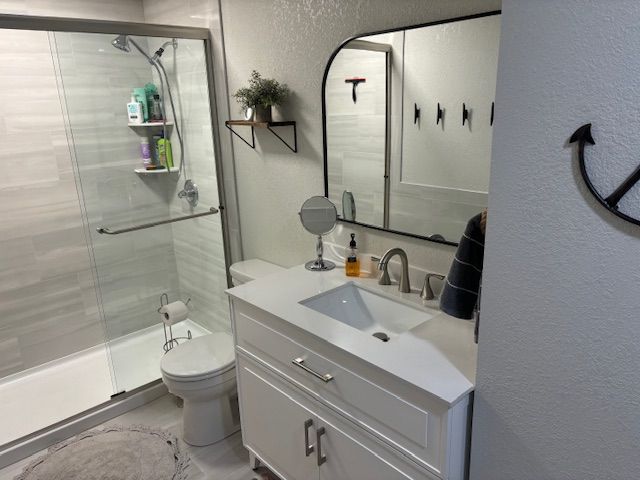 Modern bathroom with a white vanity, a glass shower, and an arched mirror.