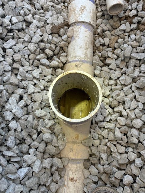 PVC pipe fitting surrounded by gravel.