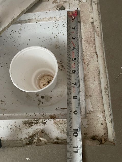 White paper cup next to a measuring tape, resting on a dirty, textured surface.