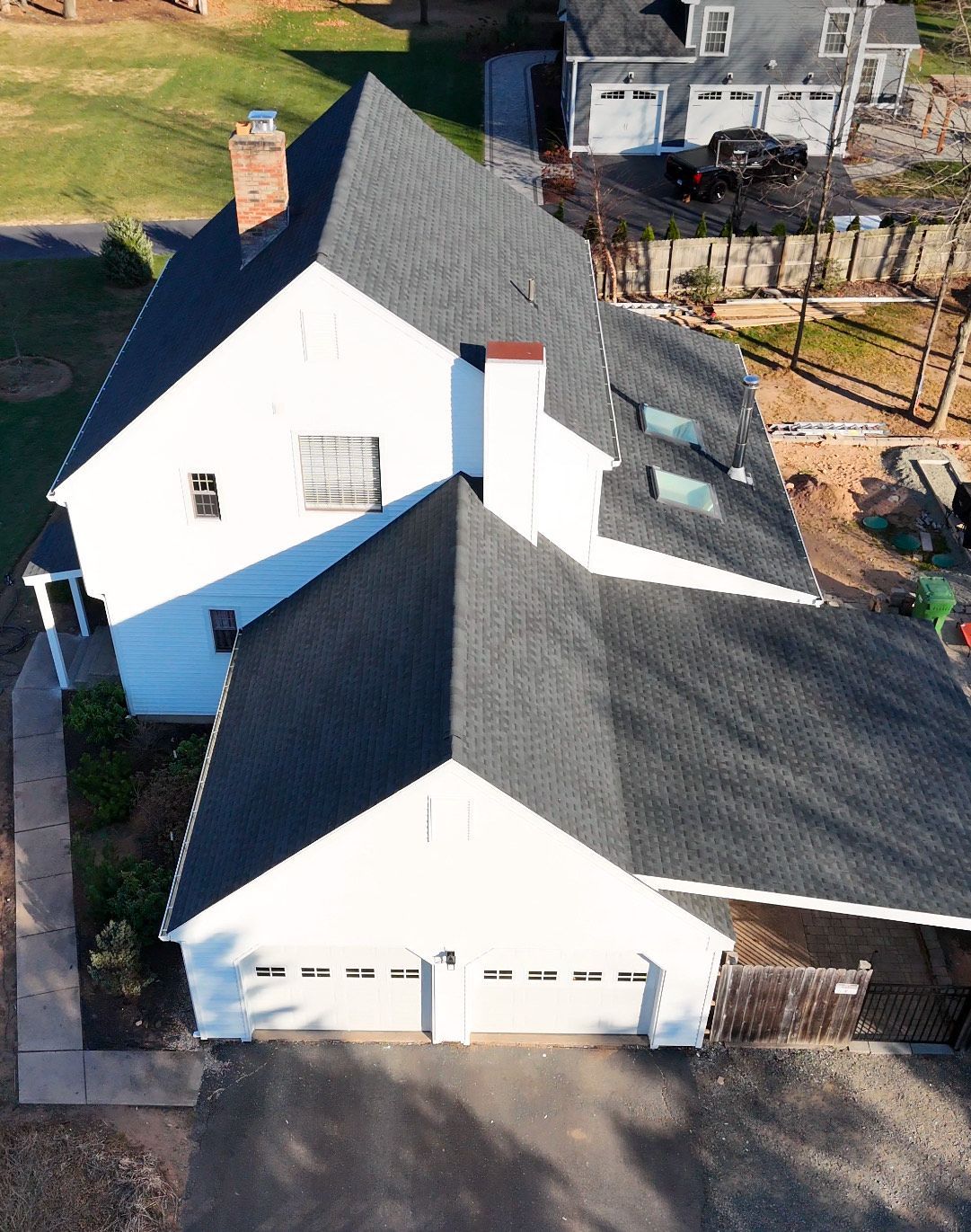White house with dark gray roof, two-car garage, and a brick chimney.