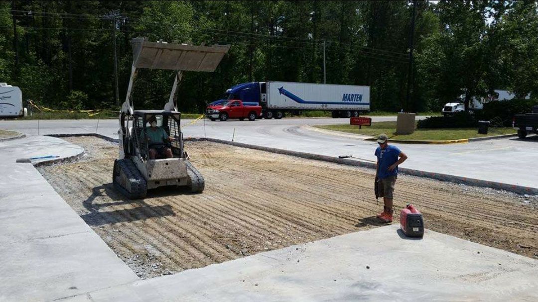 A man is standing next to a bulldozer in a parking lot.
