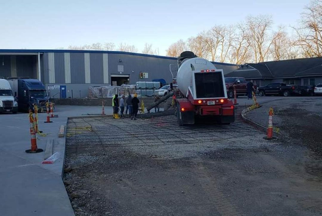 A concrete mixer truck is pouring concrete into a parking lot.