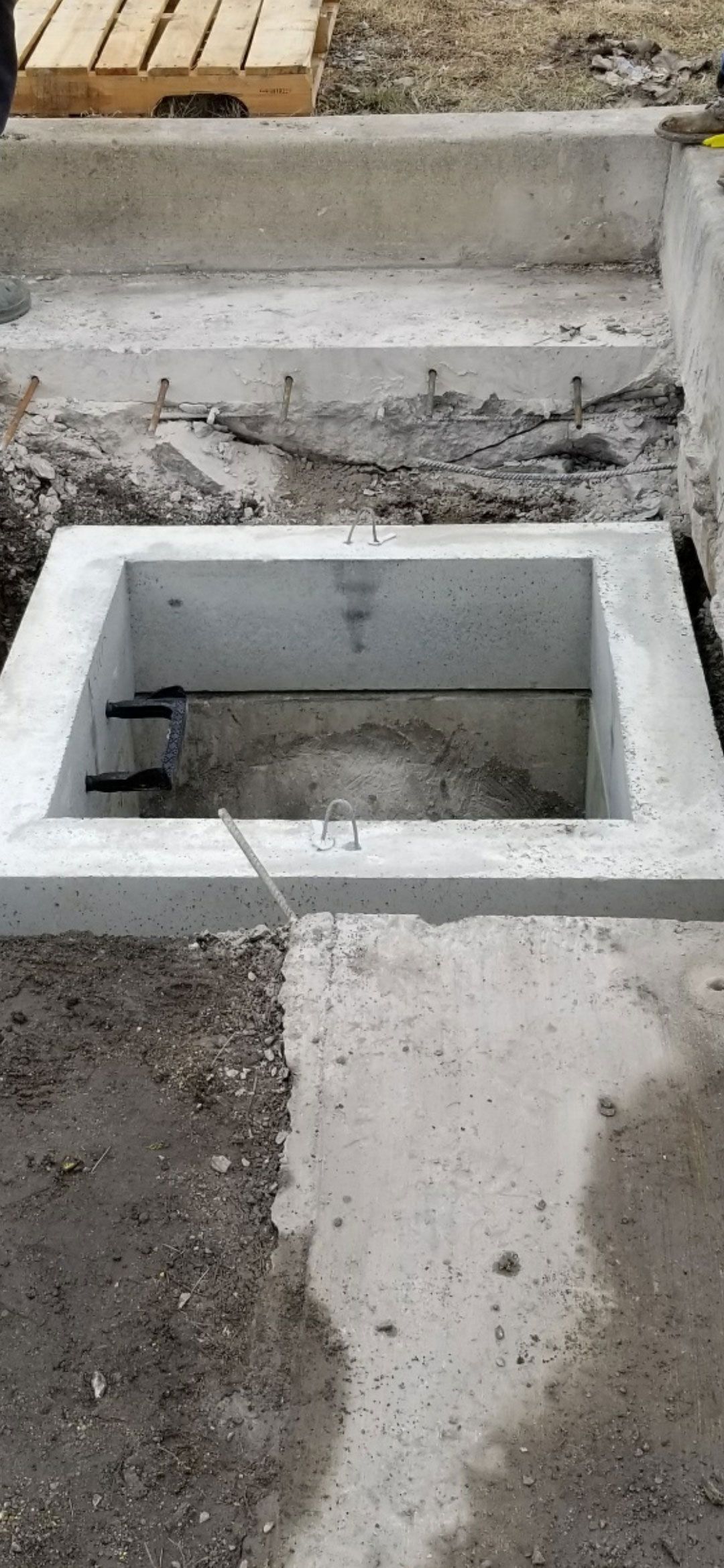 A concrete box is sitting on the ground next to a wooden staircase.