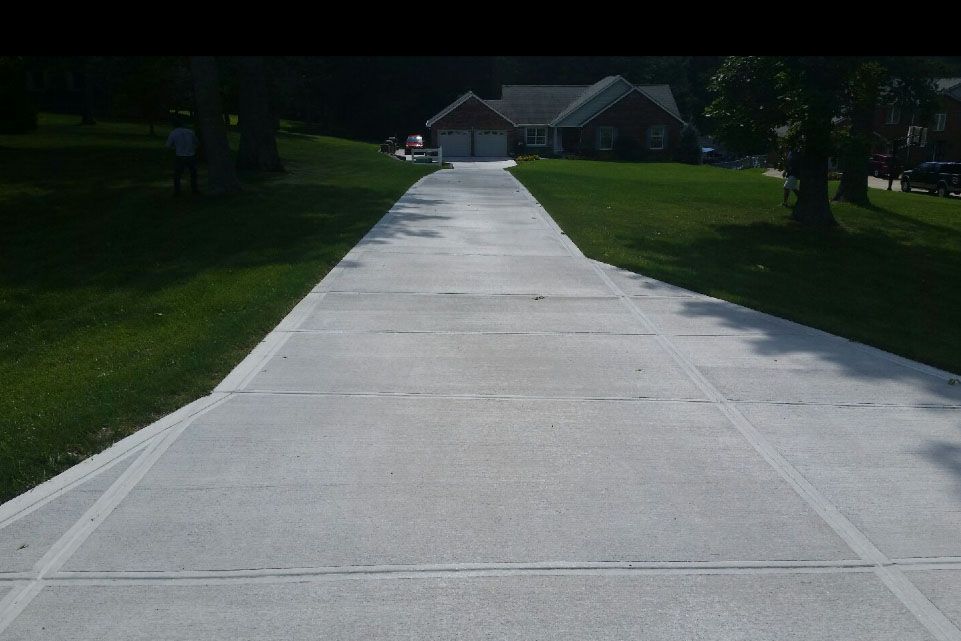 a concrete driveway leading to a brick house
