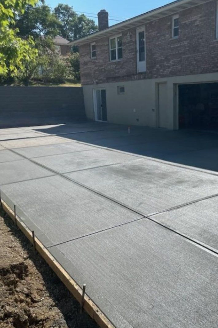 a concrete driveway is being built in front of a brick house