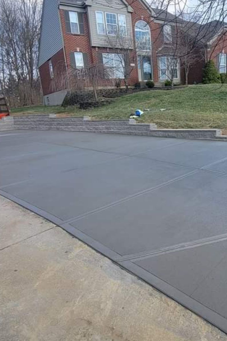 a concrete driveway with a brick house in the background