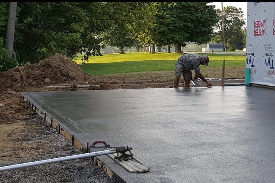 a man working on a concrete floor in a yard