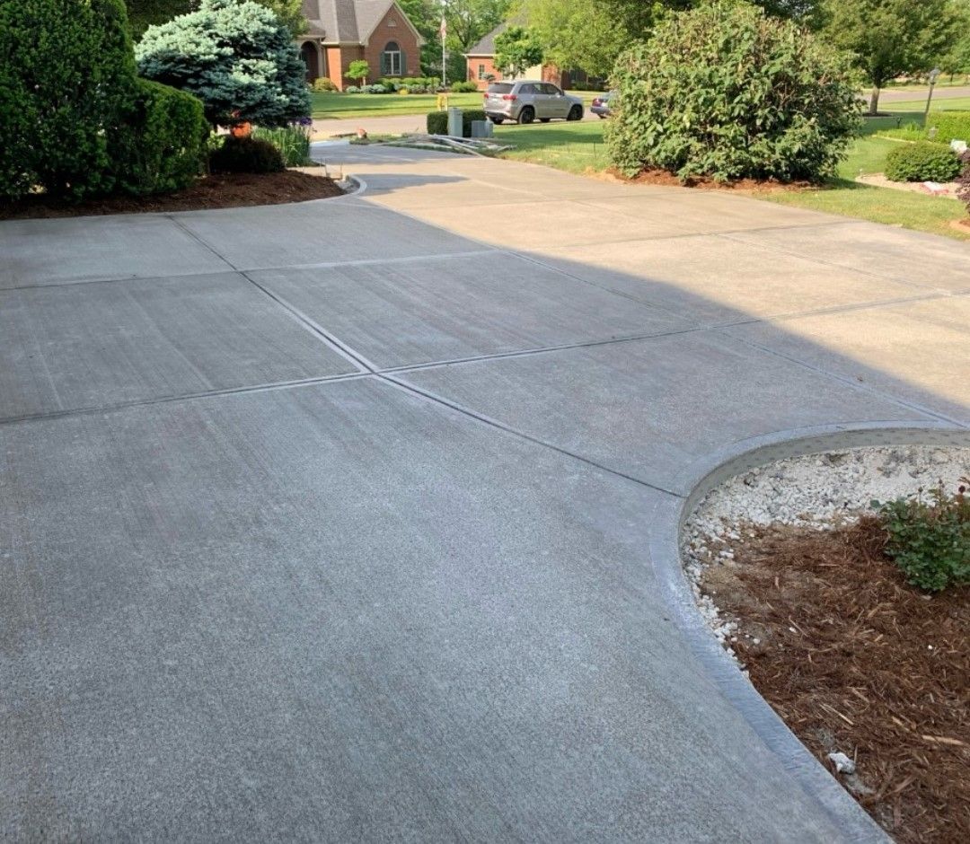 a concrete driveway leading to a house with a car parked in the background