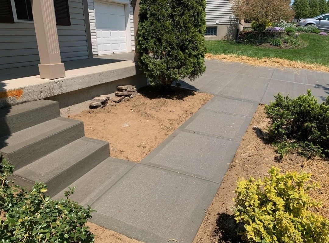 a concrete walkway with stairs leading up to a house