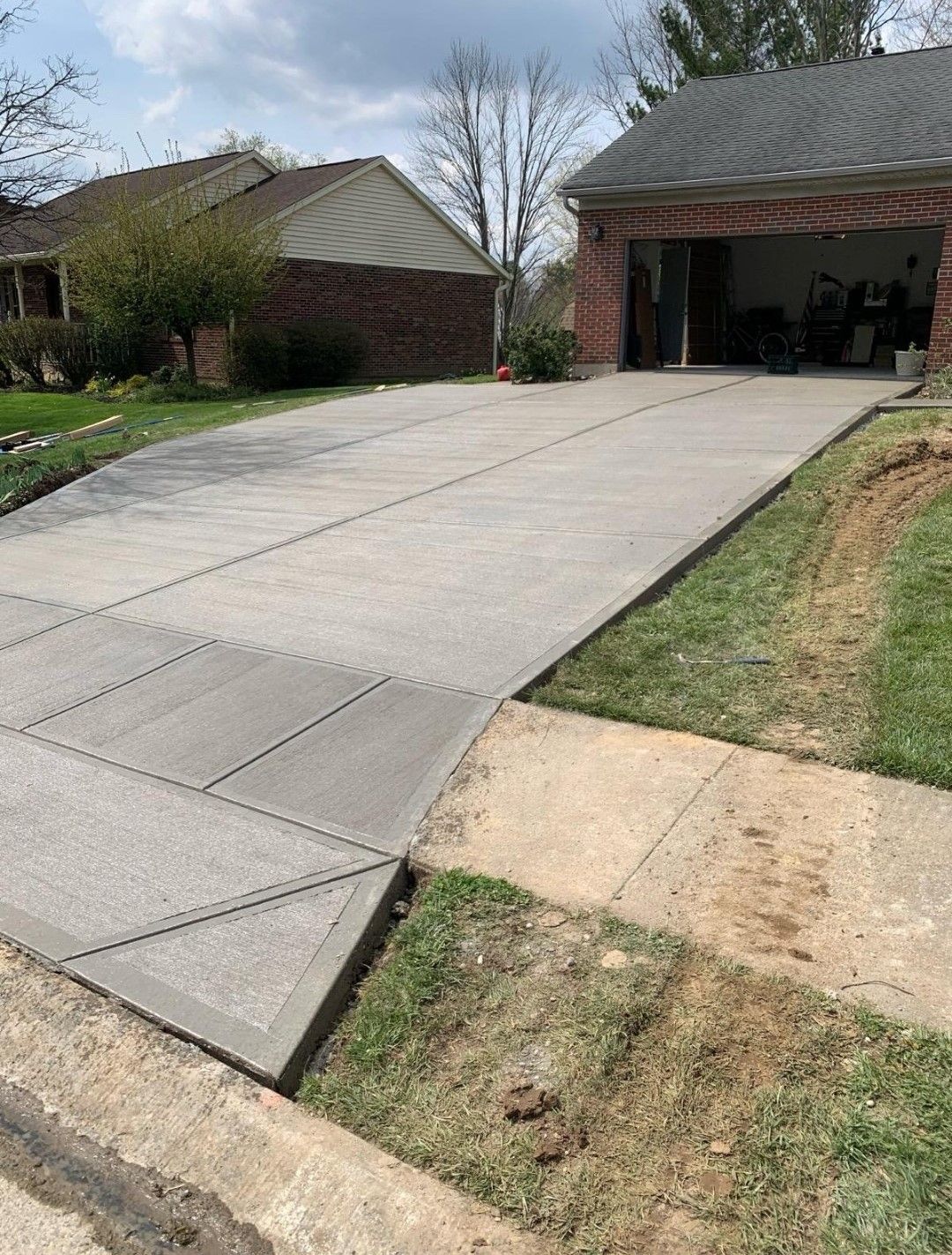 a concrete driveway is being built in front of a brick house