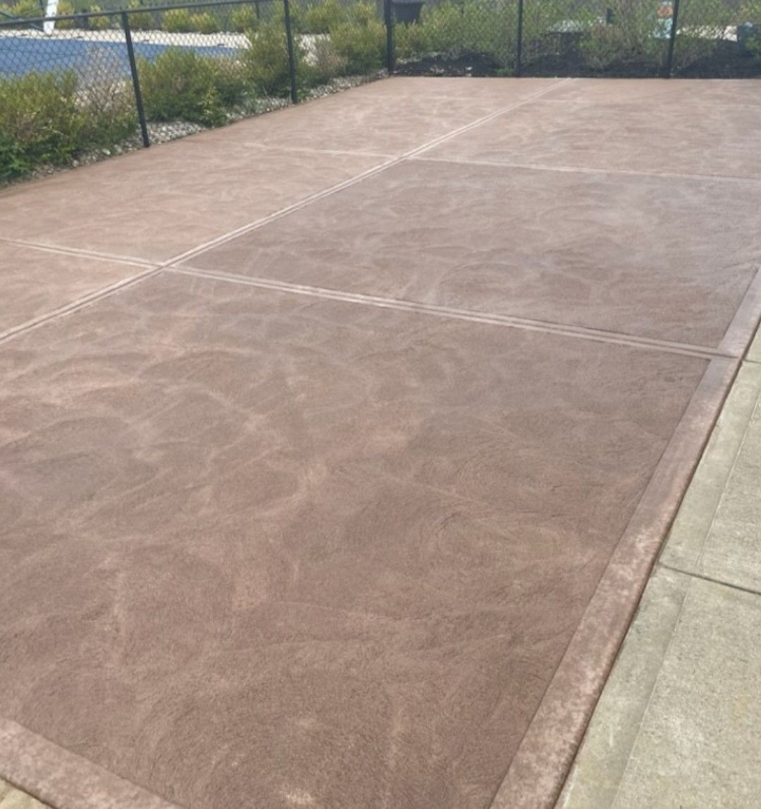 a brown concrete driveway with a fence in the background