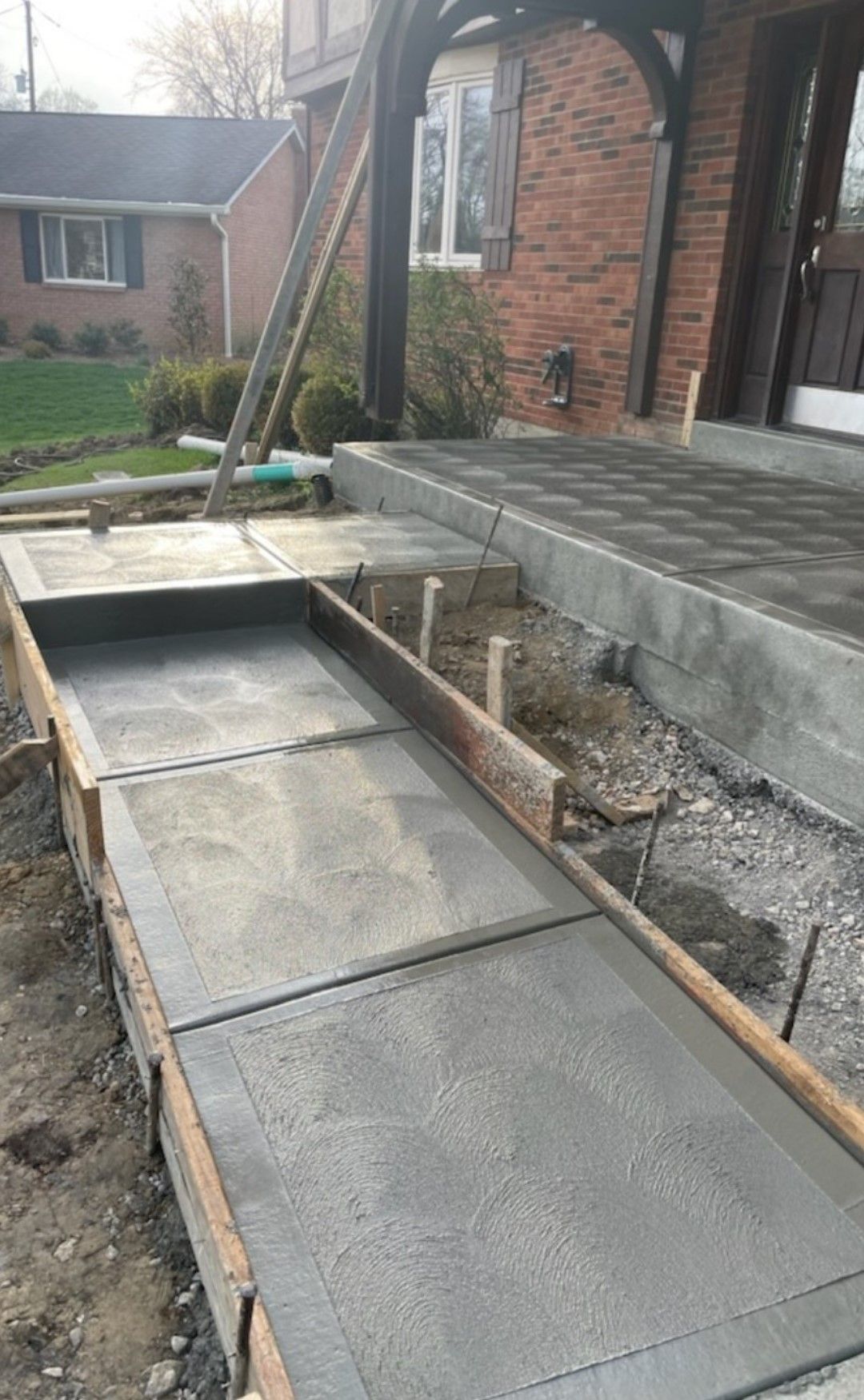 a concrete walkway is being built in front of a brick house